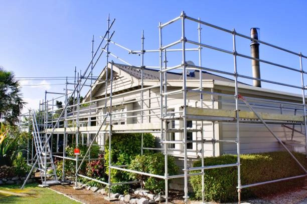 A house surrounded by metal scaffolding, undergoing renovation or maintenance work. -exterior home remodel