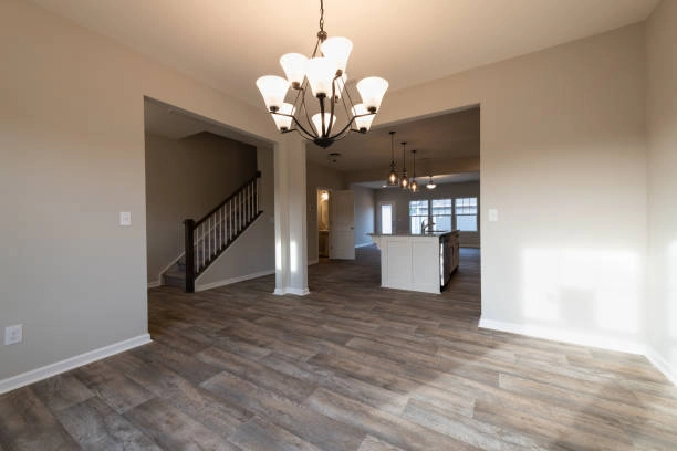 Open-concept dining area with wood-look flooring and modern chandeliers. -flooring contractors